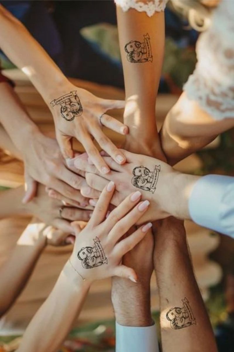 Les invités qui s'amusent avec les tatouages éphémères à l'effigie des mariés.